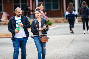 two students talking and walking through campus